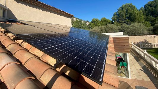 Panneaux solaires installés sur un toit de tuiles rouges avec un ciel bleu en arrière-plan