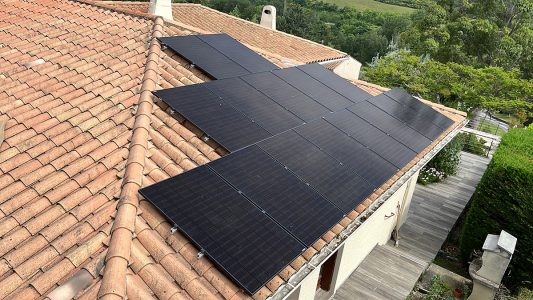 Panneaux solaires noirs sur un toit en tuiles rouges, énergie renouvelable et durabilité.