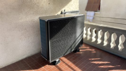 Unité extérieure de climatisation, installée à l'extérieur sur un sol carrelé, contre un mur blanc