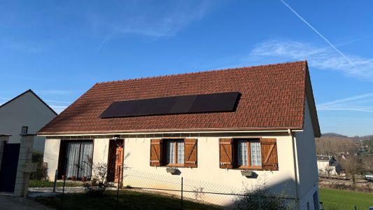 Une maison avec des panneaux solaires sur le toit et des volets en bois.